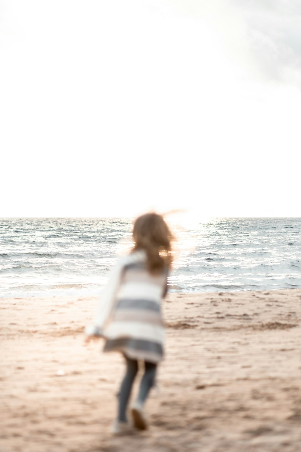 woman in white and blue stripe long sleeve shirt standing on beach during daytime