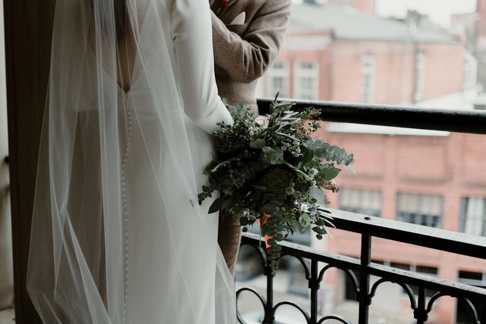 woman in brown coat holding white flowers