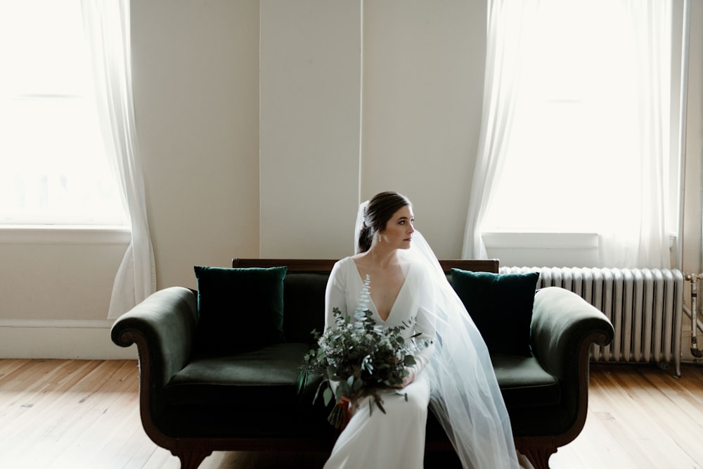 woman in white wedding dress sitting on black leather couch