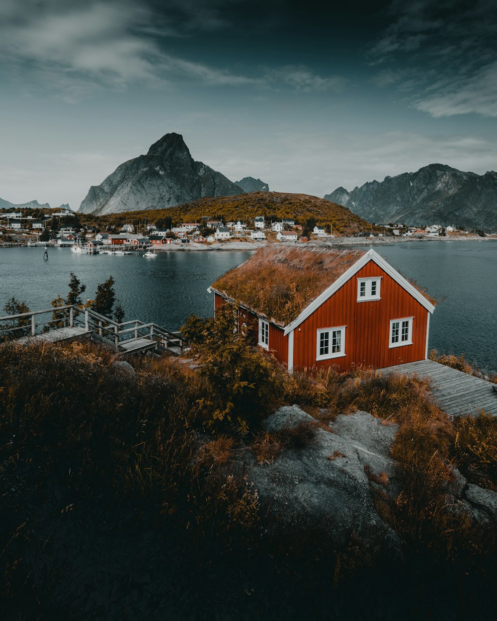 red and white house near body of water and mountain during daytime