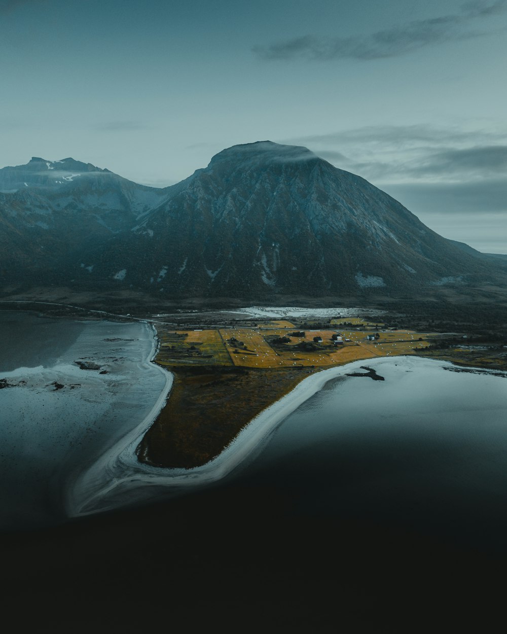 lake near mountain under cloudy sky during daytime