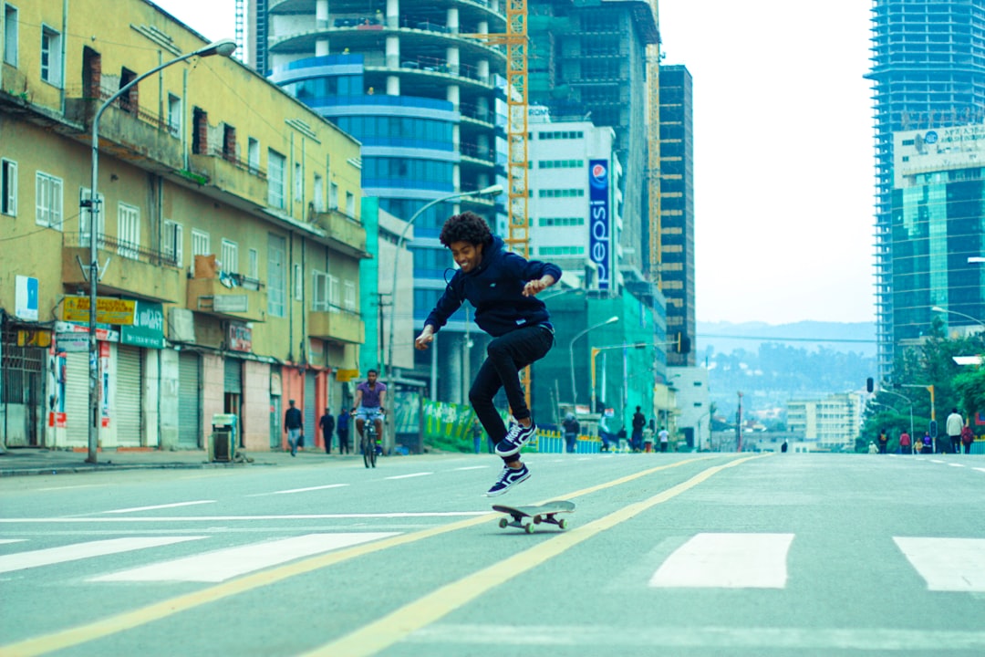 man in black shirt and black pants doing skateboard stunts on gray concrete road during daytime