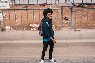 A skater wearing a black oversized hoodie and baggy pants, mid-trick on a city street.