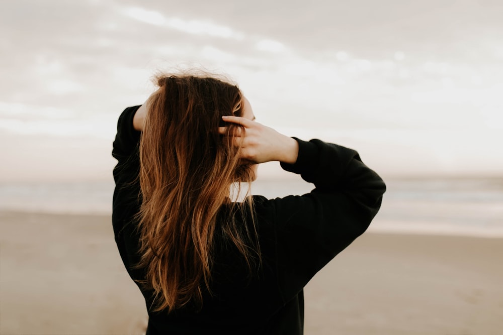 woman in black long sleeve shirt covering her face with her hands