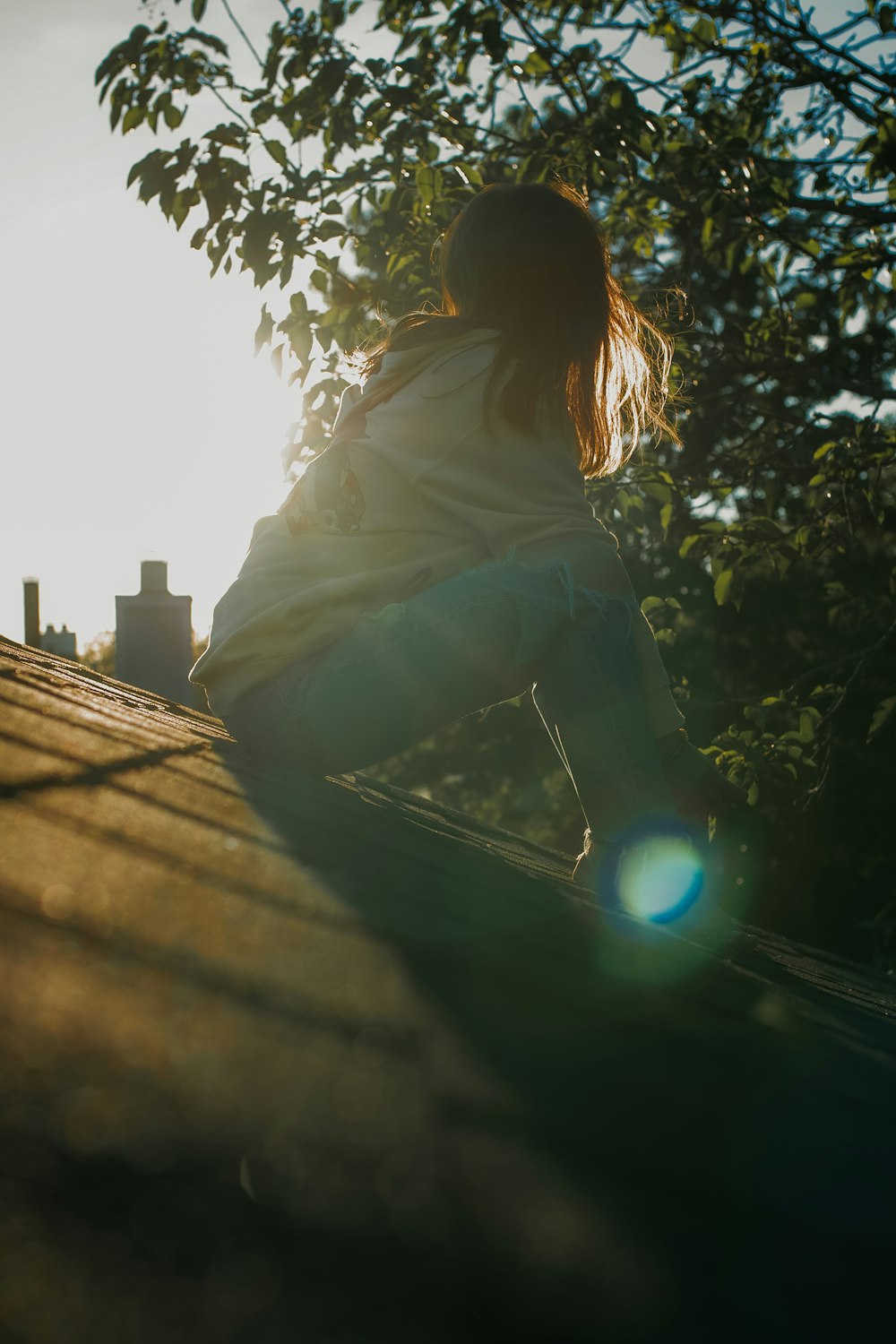 woman in white shirt sitting on brown wooden plank during daytime