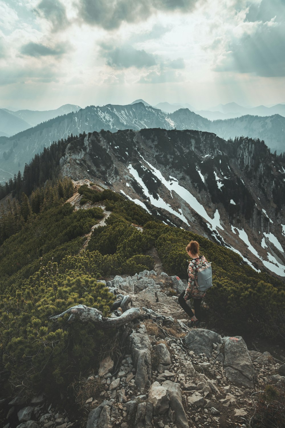 mulher na camisa branca da manga comprida sentada na rocha perto da montanha durante o dia