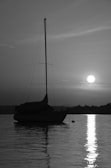 A captain steering a boat with the sun setting behind the silhouette of Mallorca’s coastline.