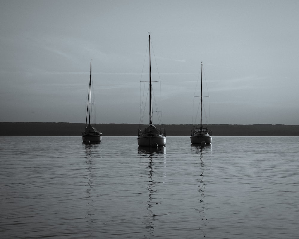 two sail boats on sea under gray sky