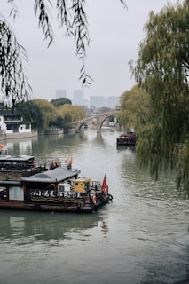 A serene riverside scene in Dali, with traditional Chinese boats and misty mountains in the background.