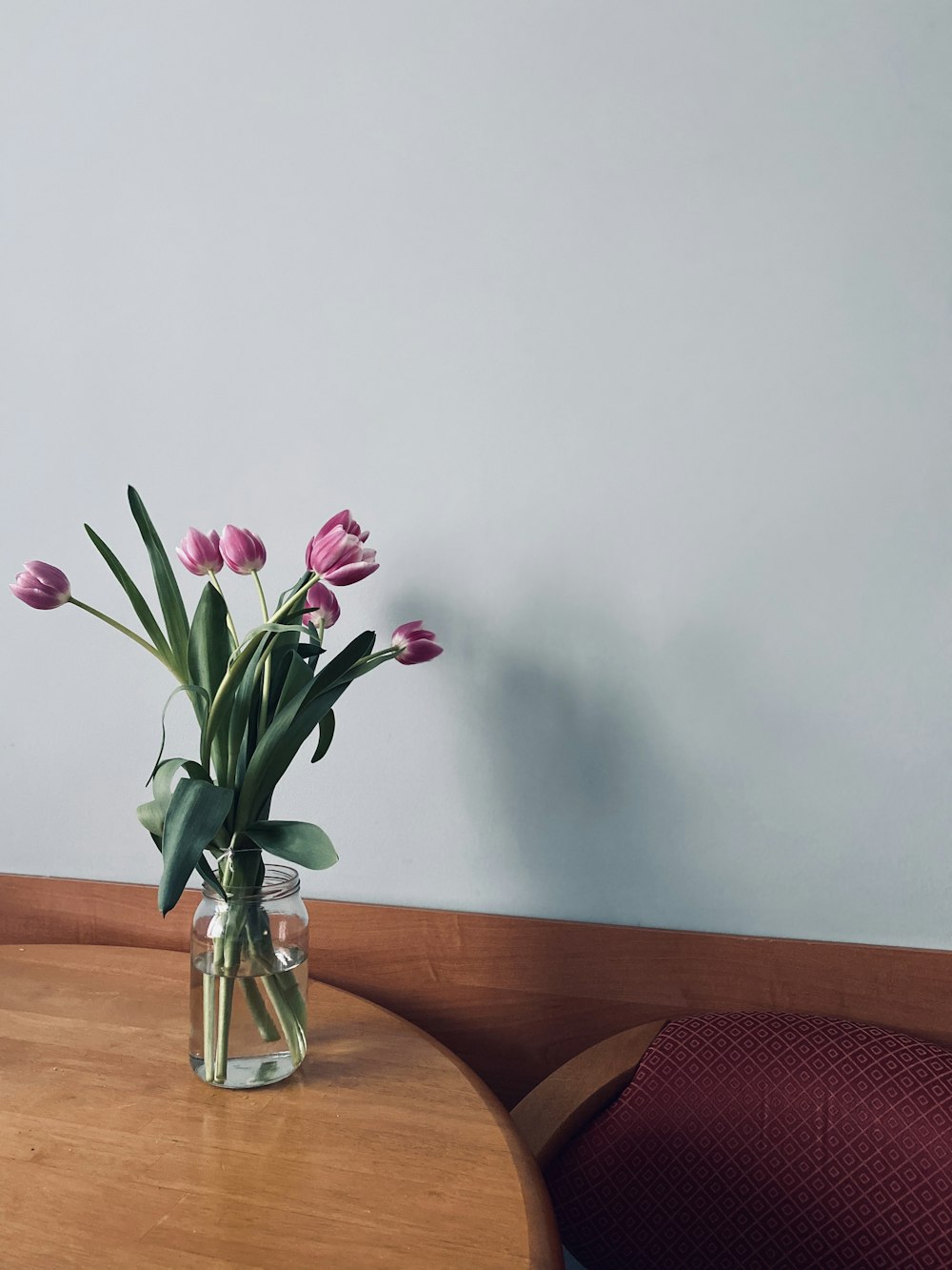 pink flowers in clear glass vase on brown wooden table