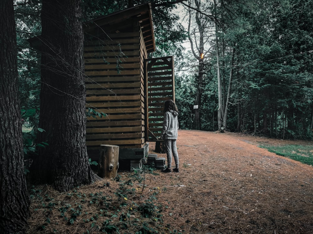 woman in gray jacket standing on brown wooden bridge