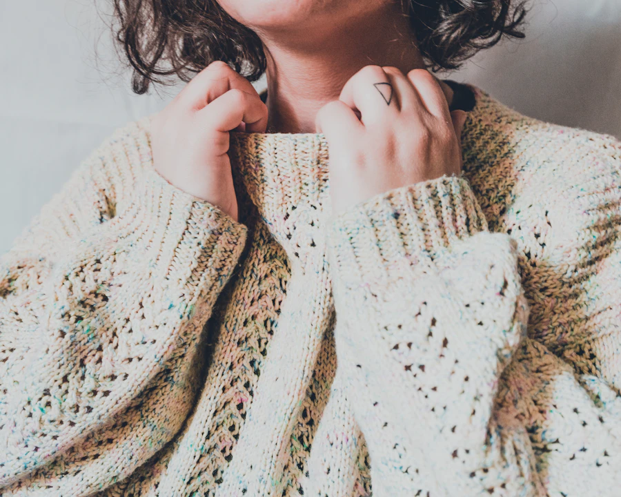 Close-up of a cream open-knit cardigan held at the collar