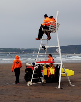 man in black shirt and black shorts sitting on red and white inflatable boat on beach