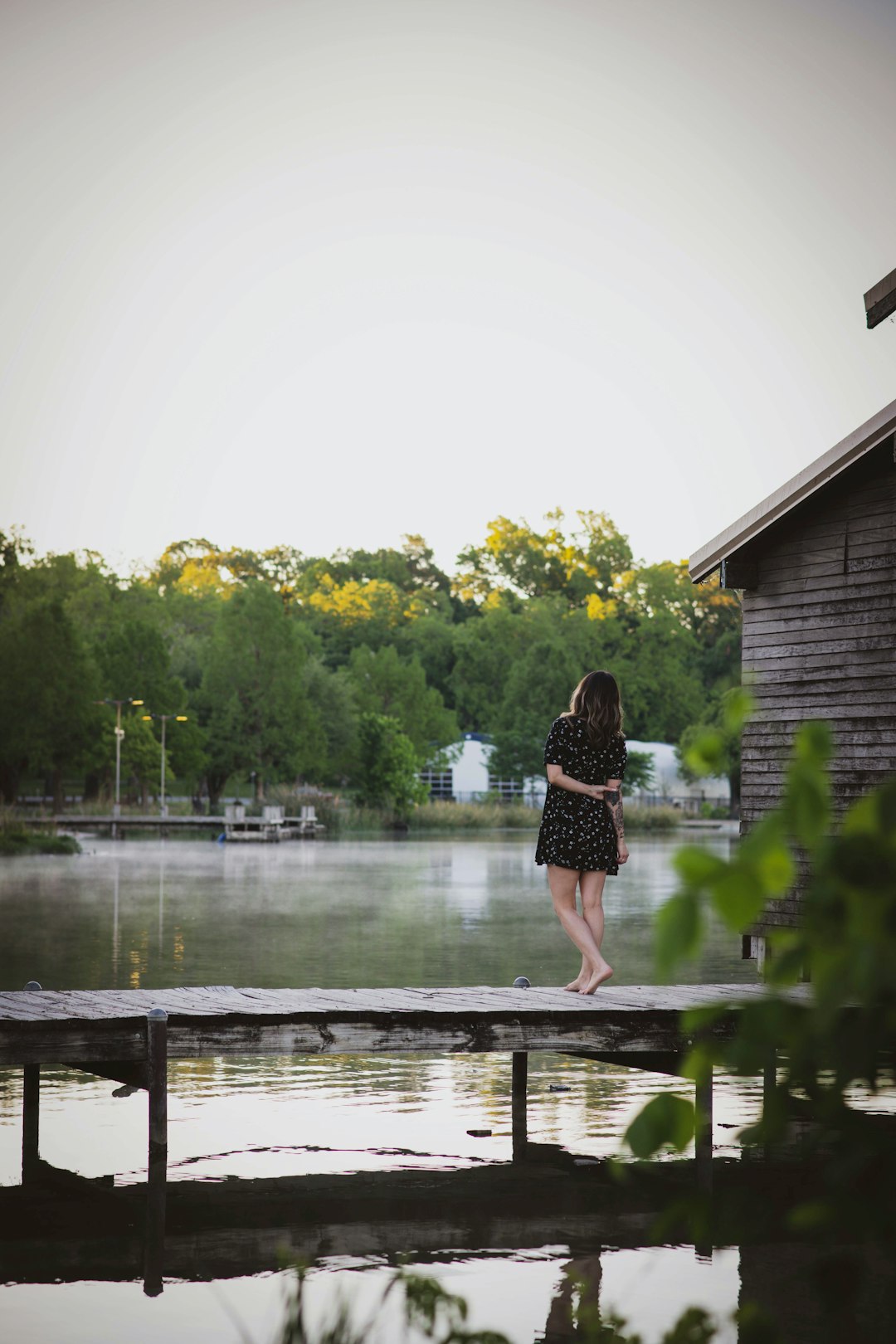 woman in black dress standing on wooden dock during daytime