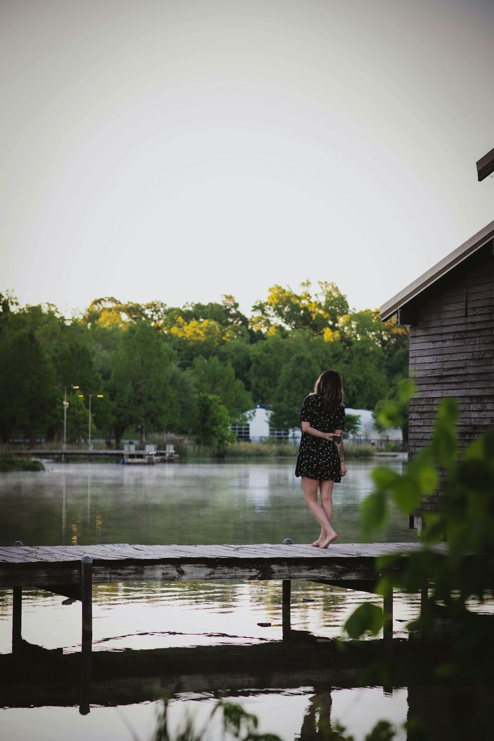 woman in black dress standing on wooden dock during daytime