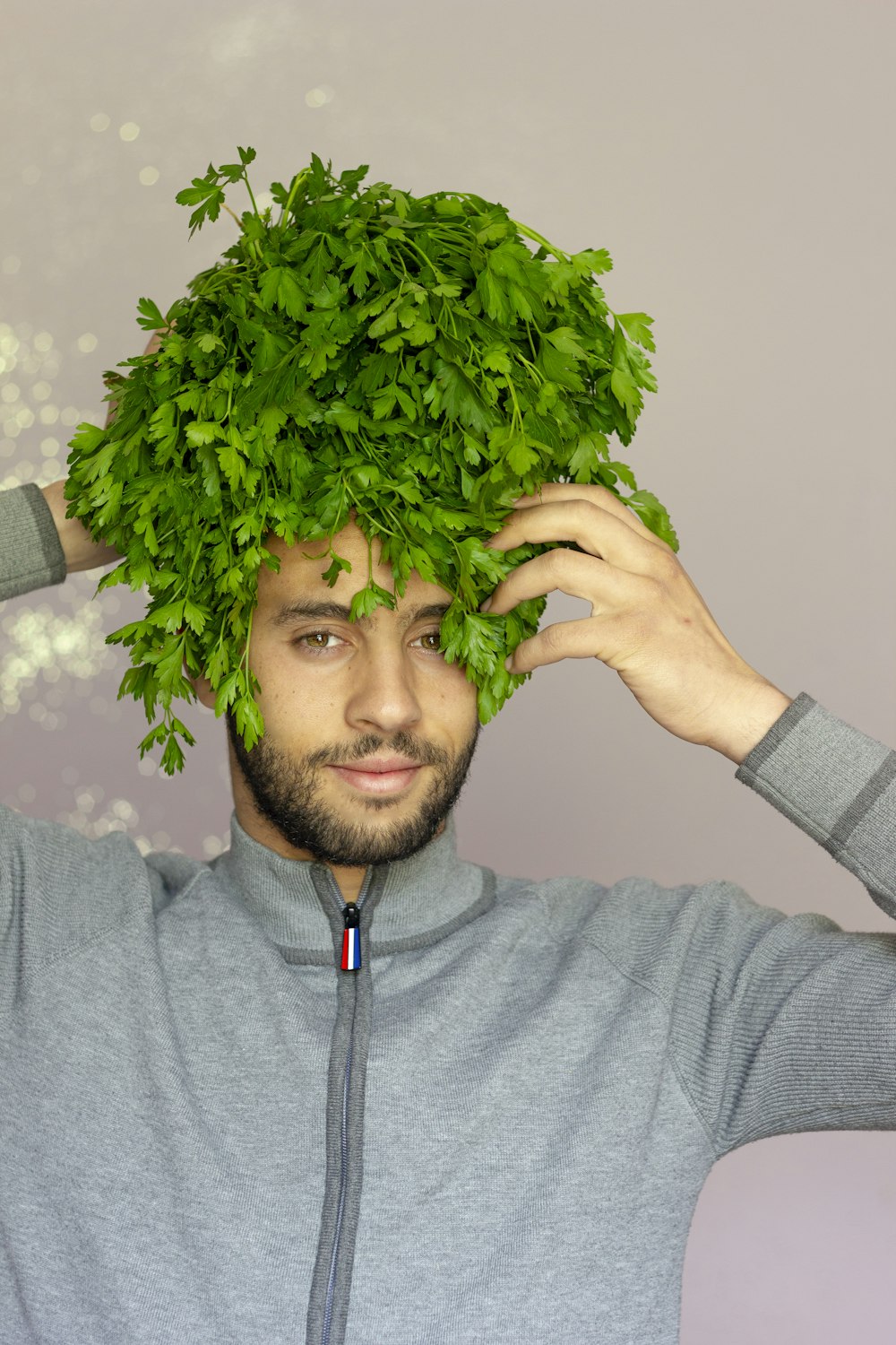 man in gray zip up jacket holding green plant