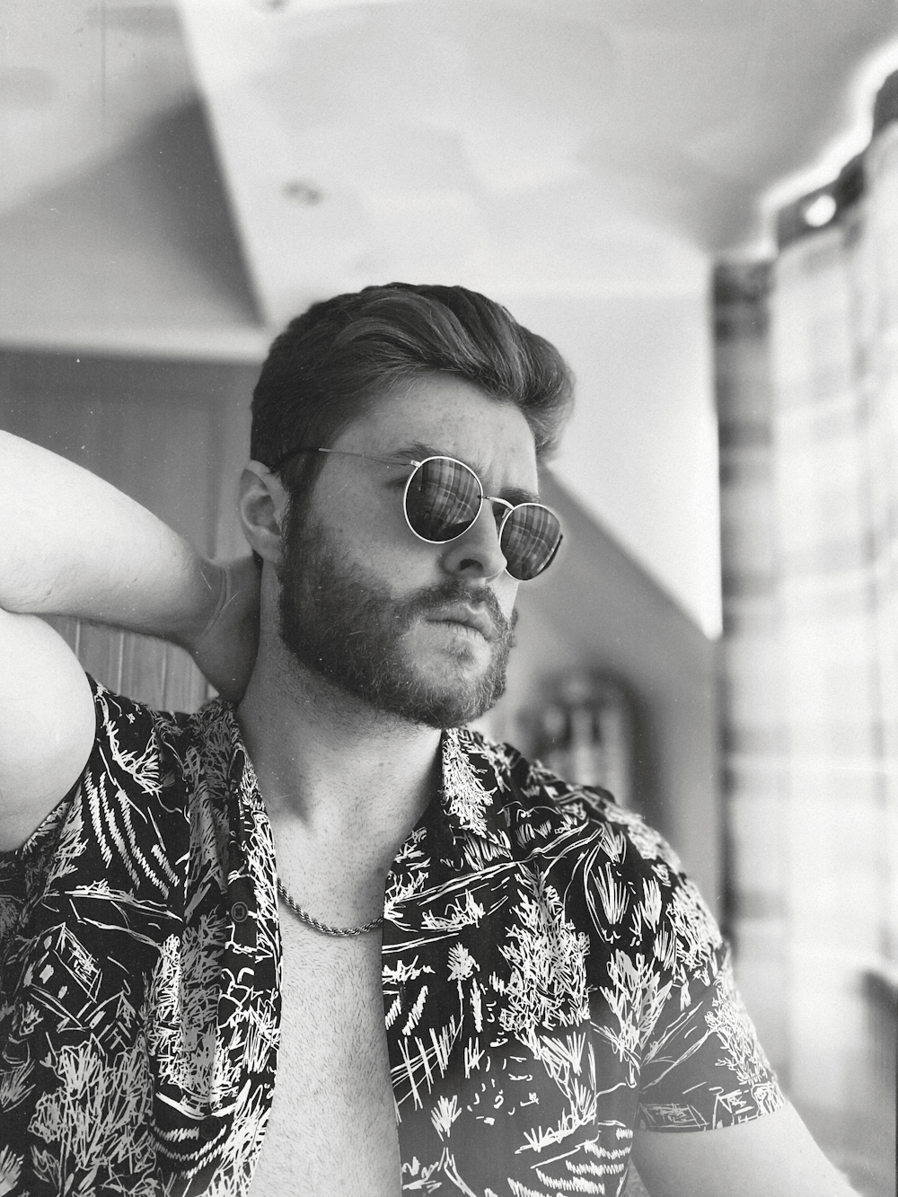 grayscale photo of man wearing sunglasses and floral shirt