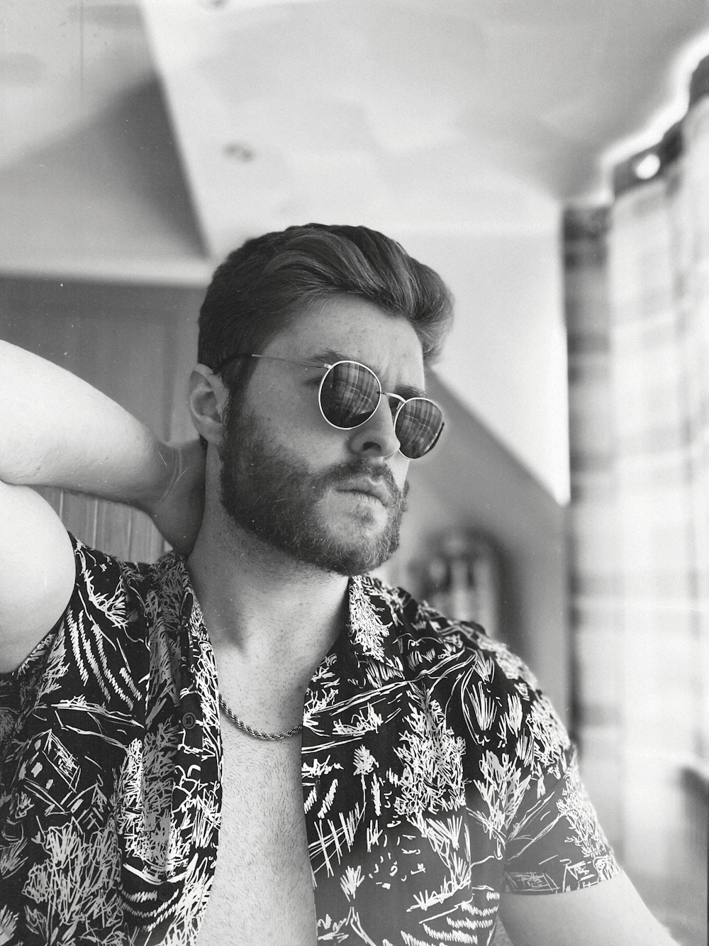 Photo en niveaux de gris d’un homme portant des lunettes de soleil et une chemise à fleurs