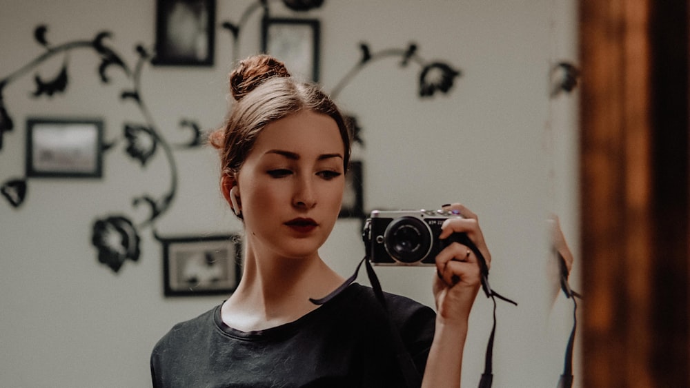 woman in gray crew neck shirt holding black and silver camera