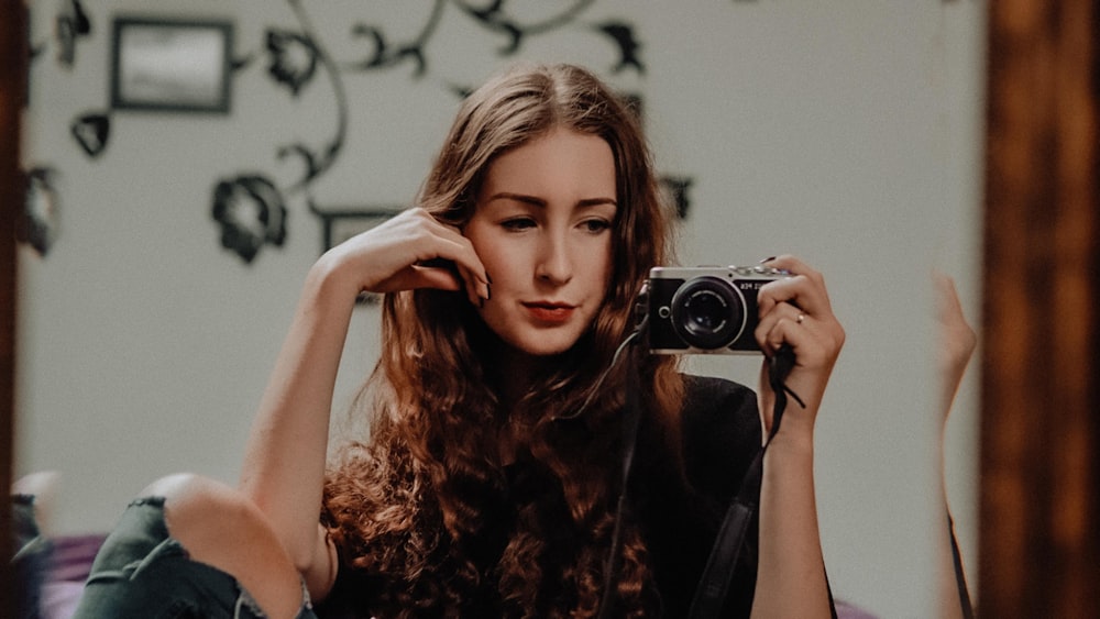 woman in black and brown floral sleeveless dress holding black and silver camera