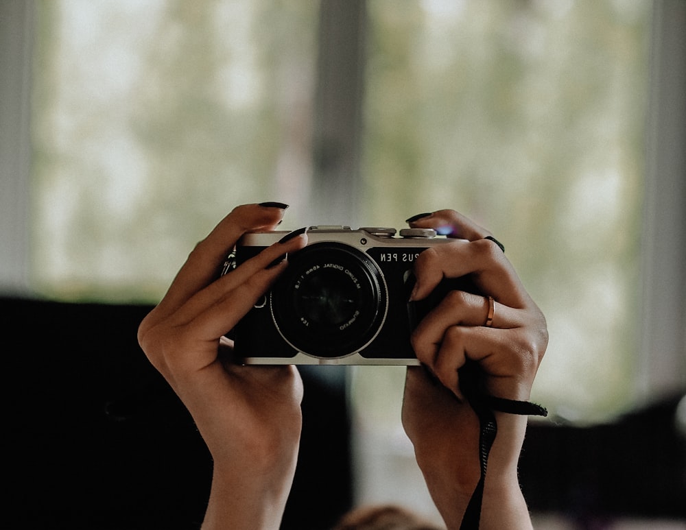 person holding black and silver camera