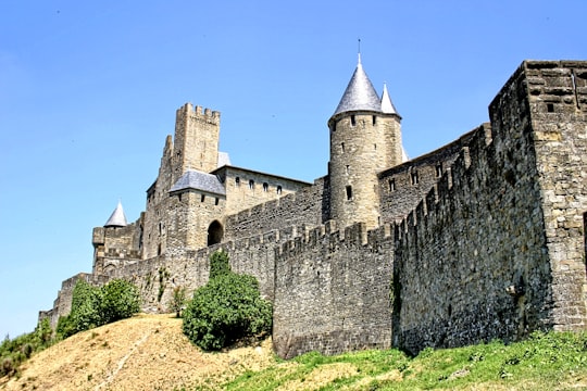 grey concrete castle under blue sky during daytime in Fortified City of Carcassonne France