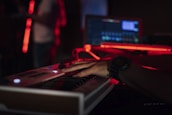 A musician playing keyboard in a dimly lit studio surrounded by instruments.