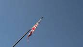 An American flag waving gently against a clear blue sky.
