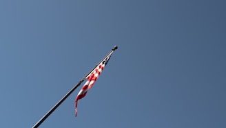 A close-up of a flag waving gently against a clear sky.