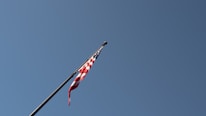 Close-up of an American flag waving gently against a clear blue sky in Idaho.