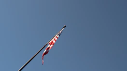 An American flag waving gently against a clear blue sky.