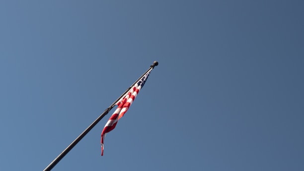 An American flag waving gently against a clear blue sky.
