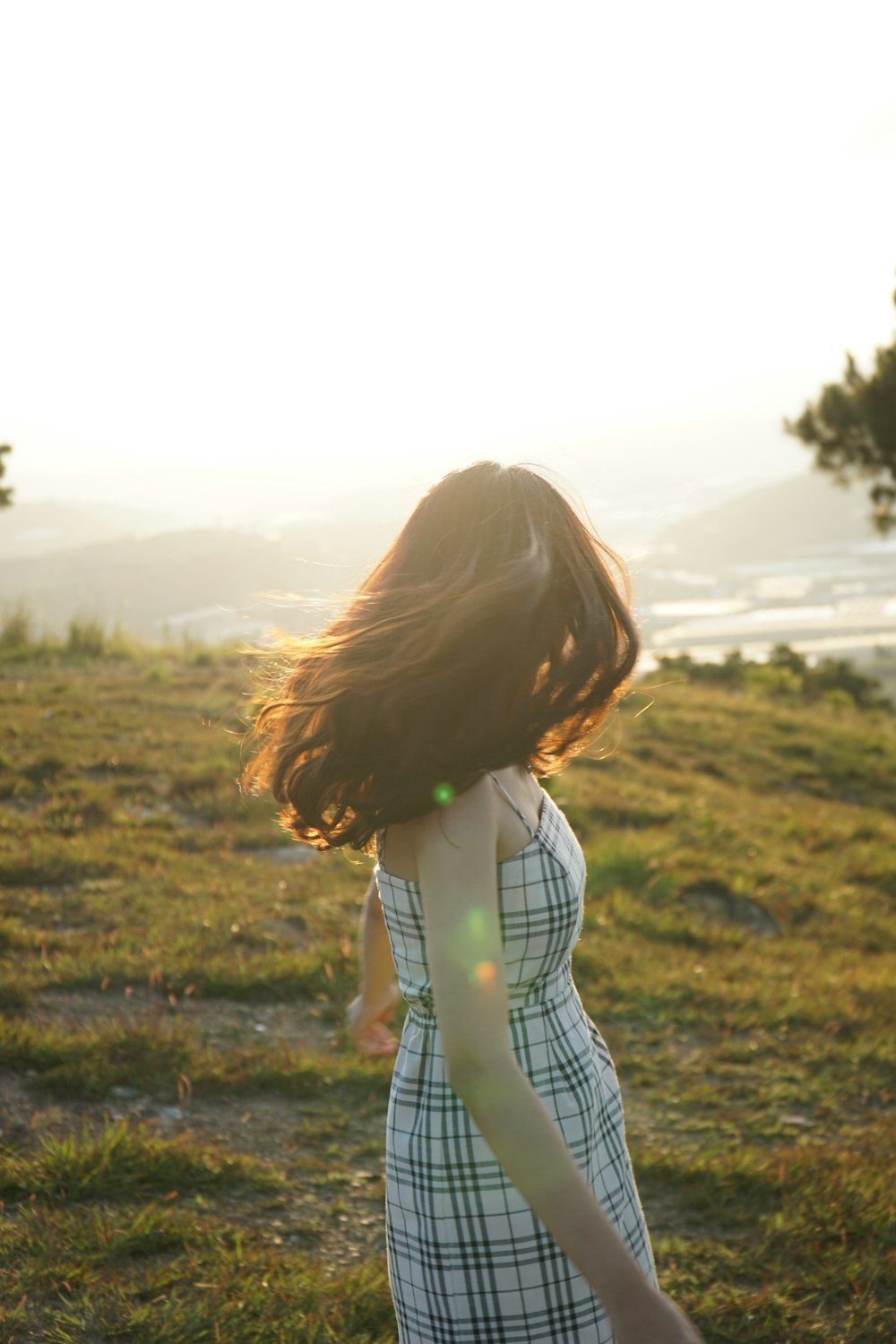 woman in white and black plaid dress shirt standing on green grass field during daytime