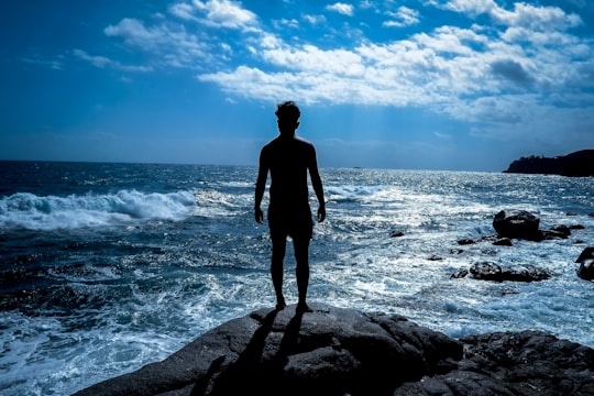 man in black jacket standing on rock near sea during daytime in Costa Brava Spain