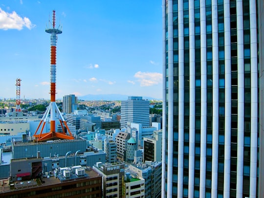 white and red tower near city buildings during daytime in Hon-Atsugi Station Japan