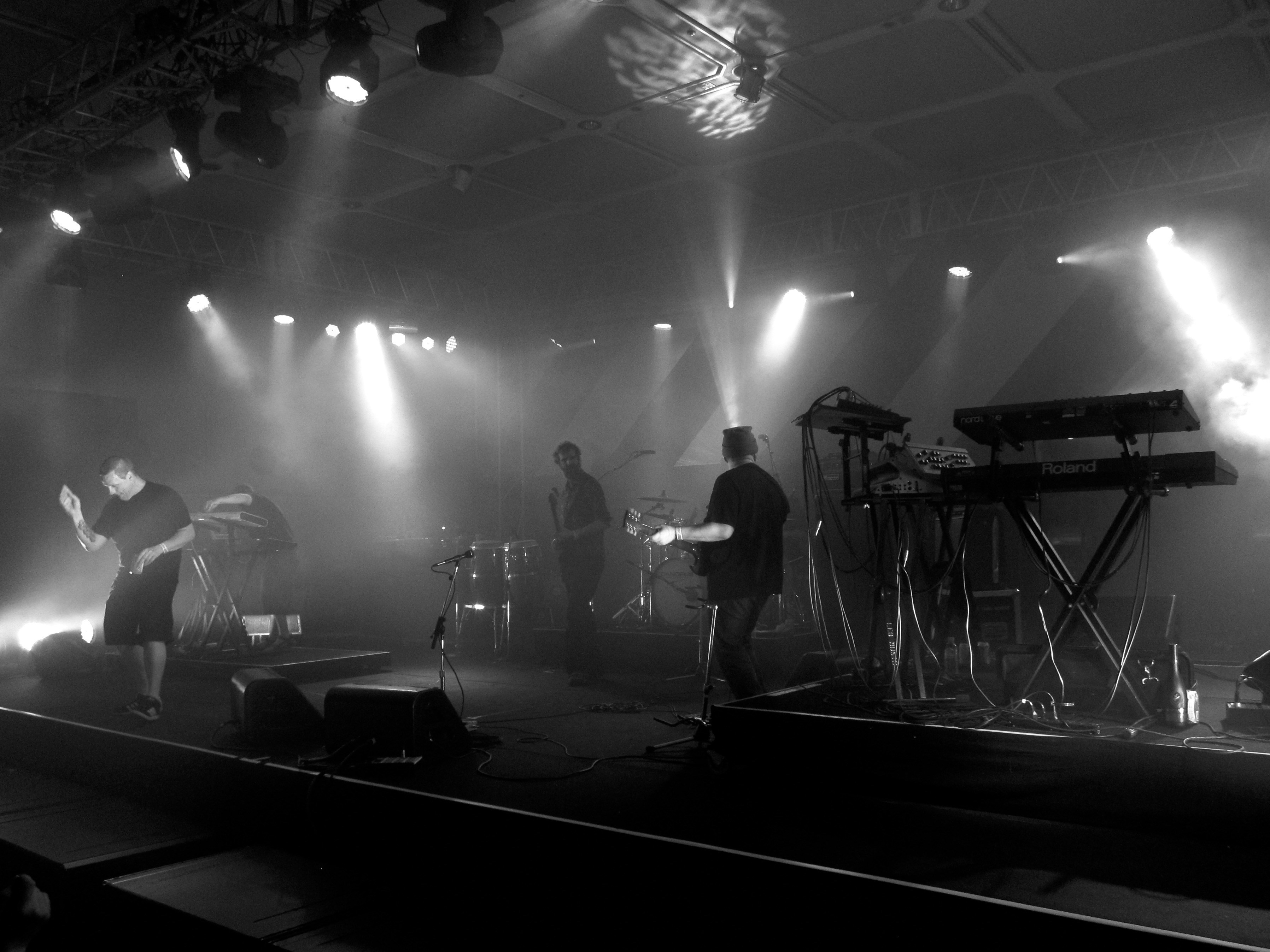 Dark atmospheric stage with heavy smoke and dim red lighting evoking doom metal atmosphere