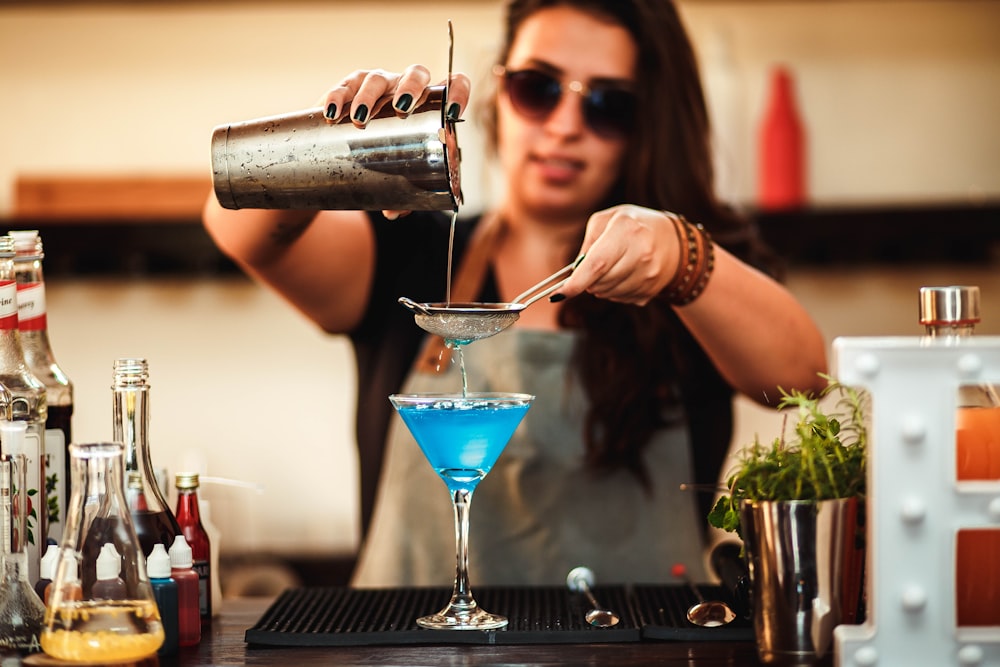 femme versant de l’eau sur un verre à cocktail