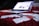 A slightly blurred laptop is open and resting on a red carpet. In the foreground, several credit cards and receipts are scattered across the carpet, suggesting a scene involving online shopping or financial transactions.