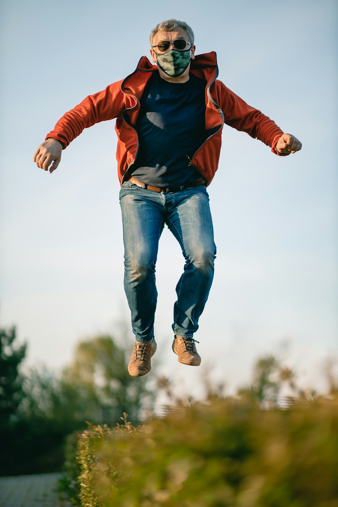 man in red jacket and blue denim jeans jumping