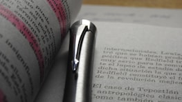 Close-up of an editor's hands marking a manuscript with a red pen.