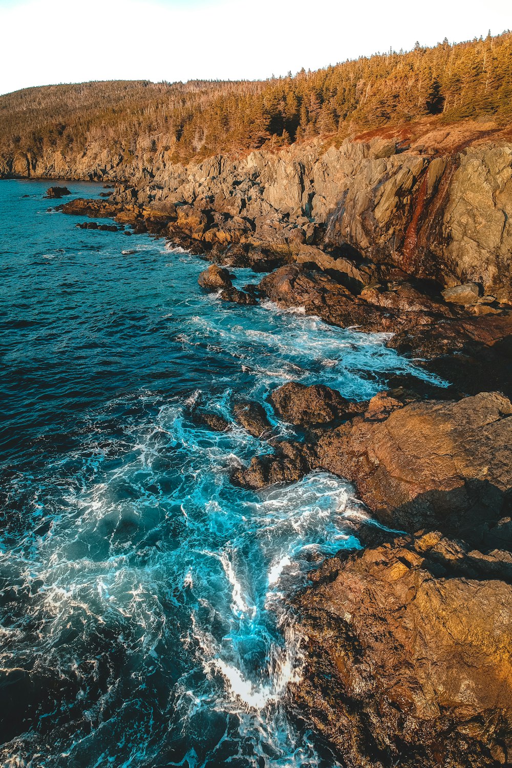 an aerial view of a rocky coastline with blue water