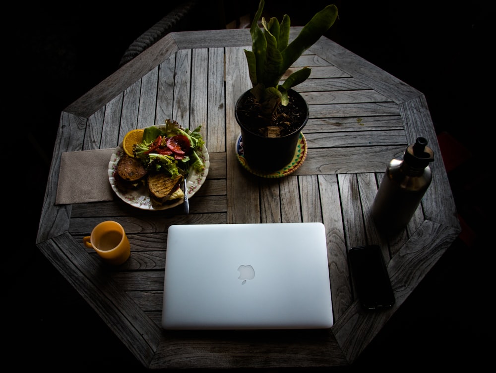 茶色の木製のテーブルの上のオレンジ色の果物の横の銀色のMacBook