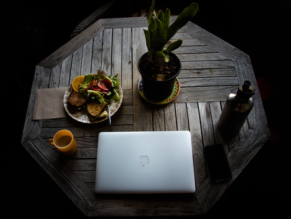 MacBook argenté à côté de fruits orange sur une table en bois marron