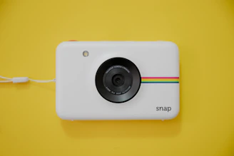 A compact instant camera producing a fresh photo under natural light.