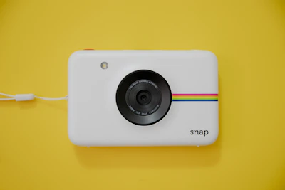 A compact instant camera producing a fresh photo under natural light.