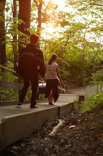 Two people walking hand-in-hand along a tree-lined path during golden hour.