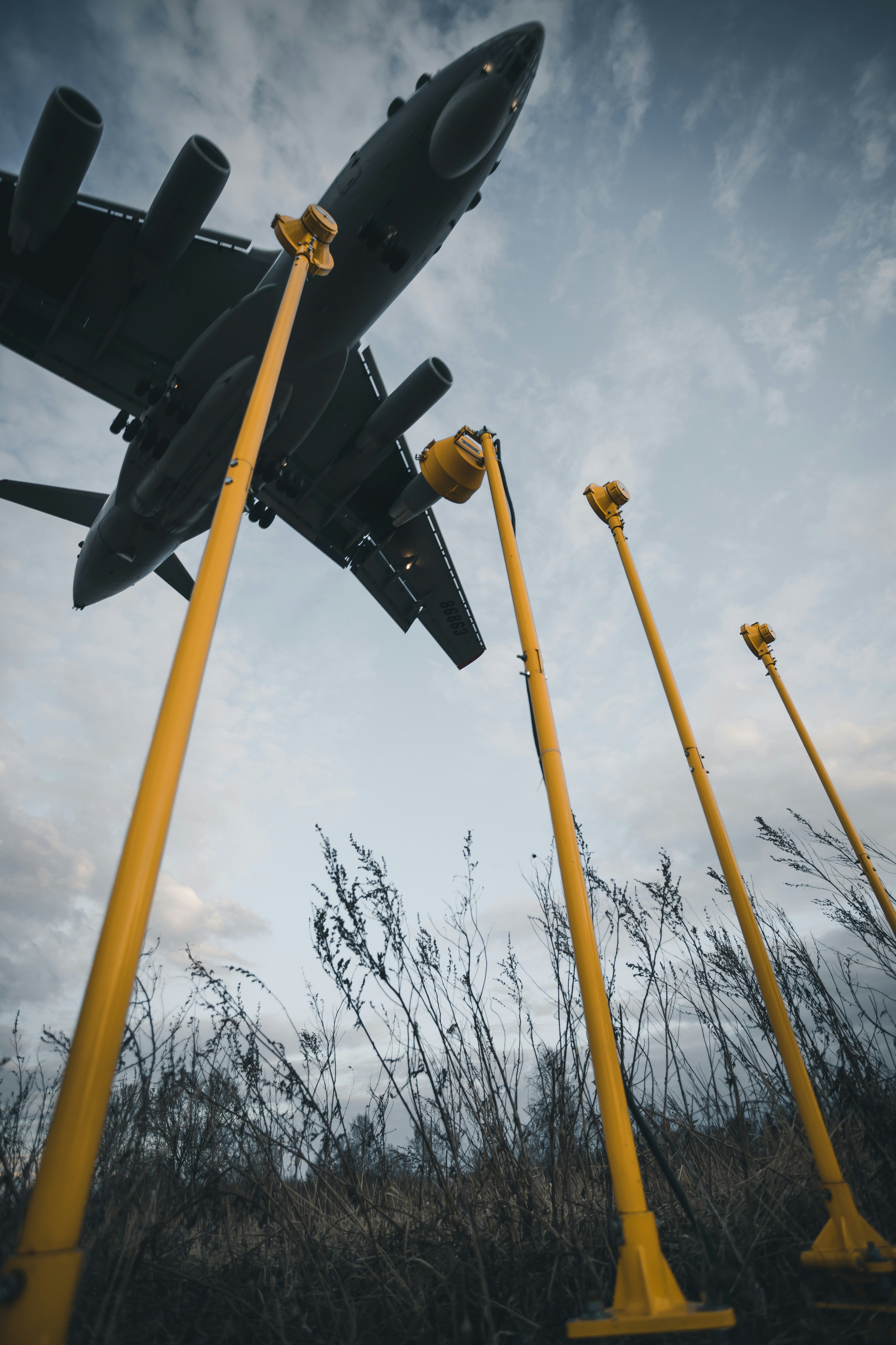 a large airplane flying over a field of tall grass