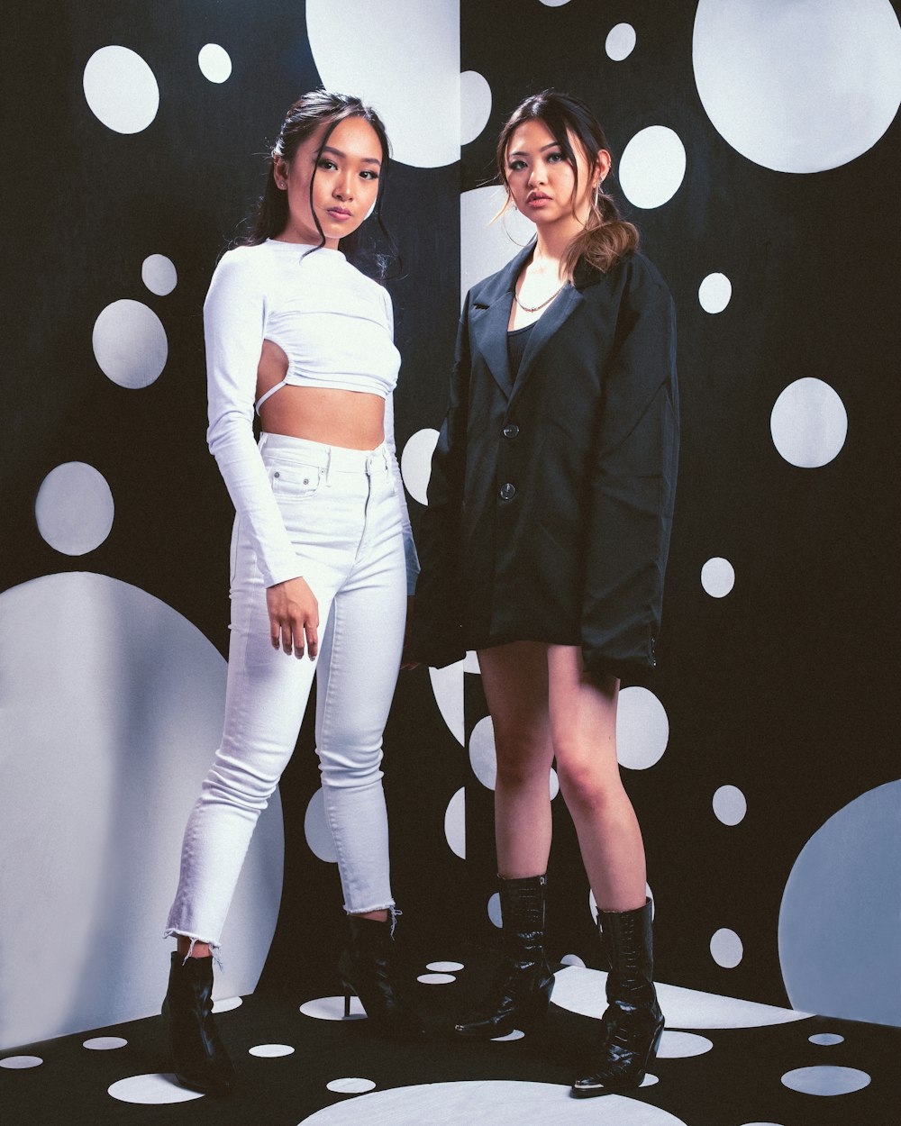 2 women in black blazer standing beside white wall