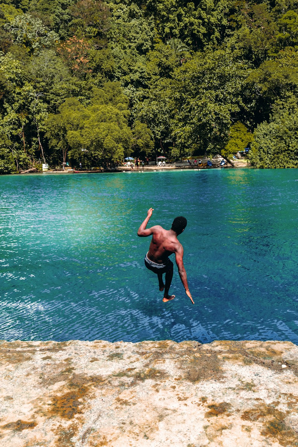 man in black shorts jumping on water during daytime