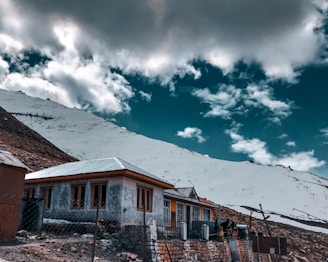 brown and white concrete house under white clouds and blue sky during daytime
